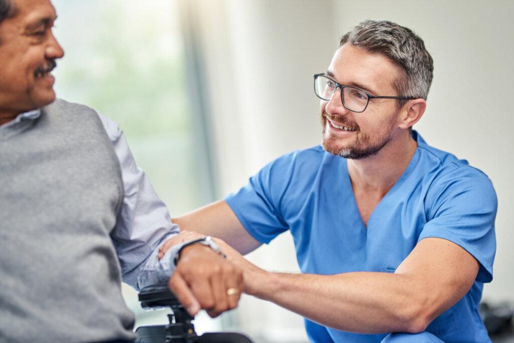 Male nurse smiling and patting the arm of a memory care resident at Traditions of Medina in Medina, OH.